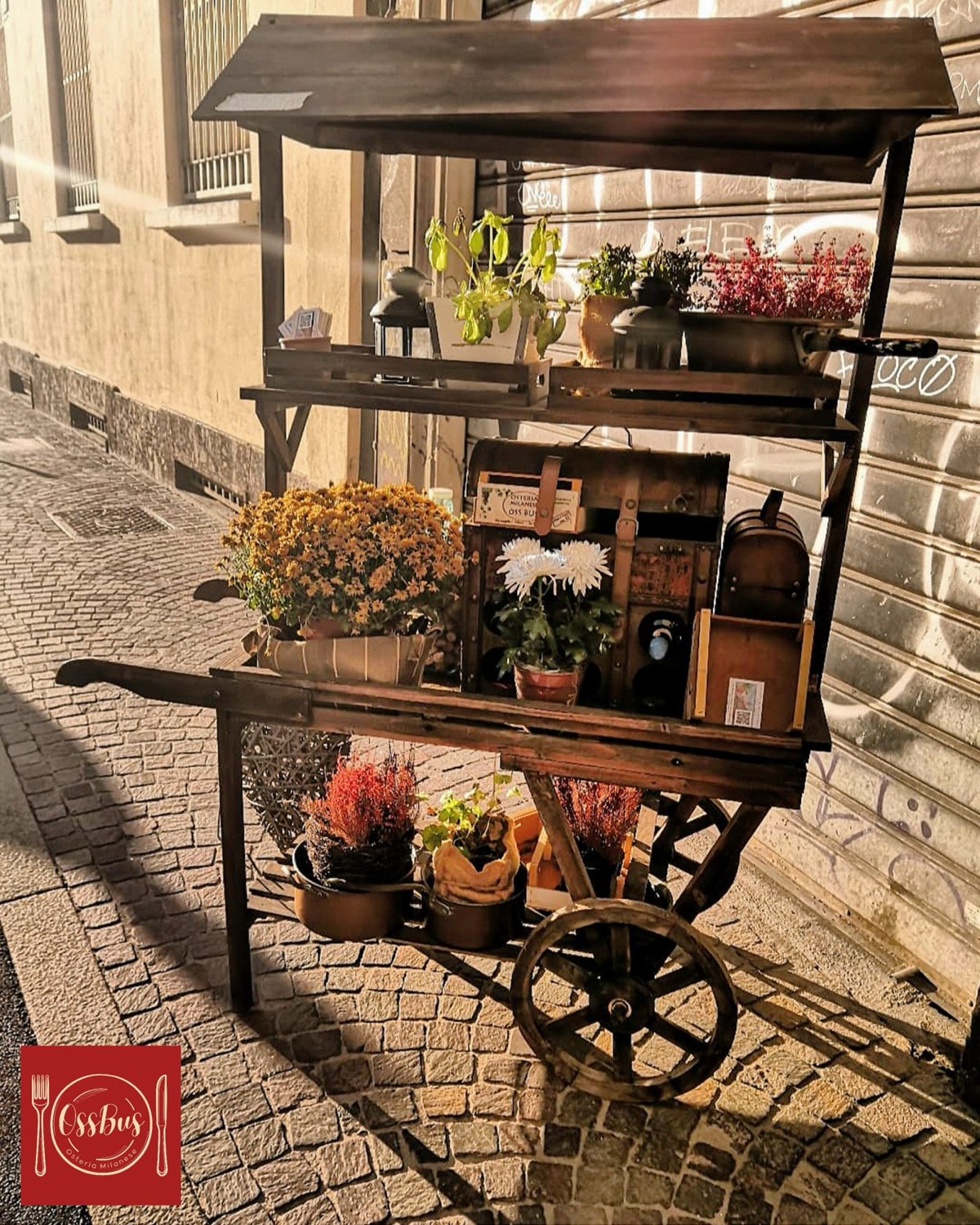 Il carretto fiorito d'epoca all'ingresso dell'Osteria Òss Bus, illuminato di sera